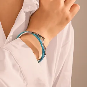Primo piano di un bracciale aperto con inserto turchese indossato al polso con camicia