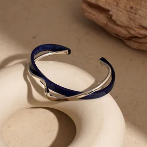 Dettaglio macro del bracciale rigido minimalista in metallo argento e acrilico blu