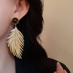 Vintage gold leaf drop earrings with tiger eye stone accent worn by an elegant model