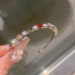 Dettaglio di un elegante bracciale rigido aperto con pietre di zircone cubico colorate.