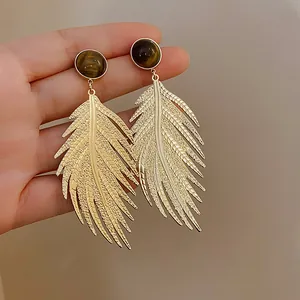 Detail view of exquisite golden leaf-shaped earrings featuring artificial tiger eye stone studs