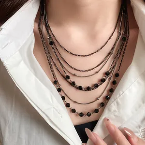 Detailed view of elegant vintage multi-layer black glass bead necklace on white shirt