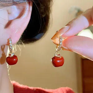 Elegant gold-plated hoop earrings with red enamel apple pendants and sparkling zircons.