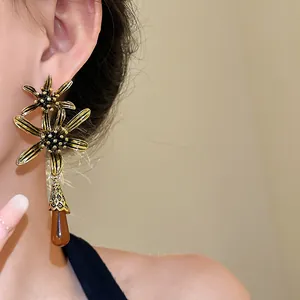 Close-up of vintage flower earrings featuring a resin amber teardrop tassel pendant.