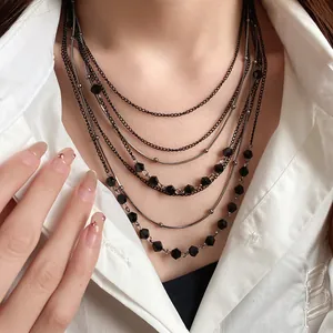 Detailed view of multi-layered vintage necklace with black glass beads and dark chains.