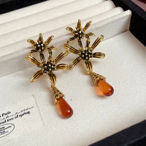 Detail of vintage flower earrings with amber resin teardrop pendants in a display box.