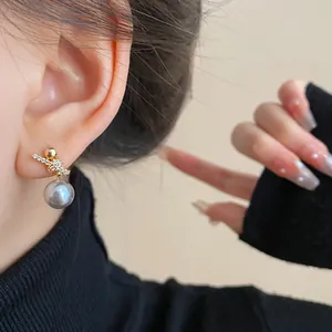 Close-up detail of elegant gold-plated zircon pearl earrings worn on a model's ear.