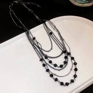 Close-up of elegant multi-layer necklace with faceted black glass beads and dark chains