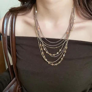 Macro detail of elegant multi-layered necklace with vintage glass beads and golden chains on model