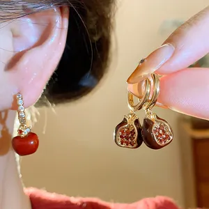 Detailed view of gold plated enamel apple and pomegranate earrings with zircons