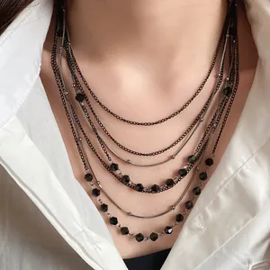 Detail of multi-layer vintage necklace featuring black glass beads on a white shirt