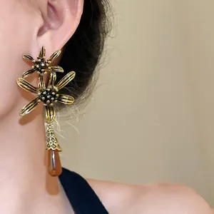 Close-up of vintage resin flower tassel earrings with golden petals and an amber water-drop