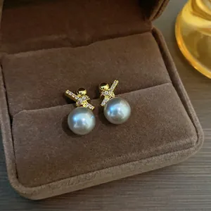 Close-up of elegant gold plated pearl earrings with sparkling zircon knot detail
