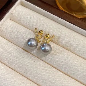 Detailed macro shot of elegant grey pearl earrings with gold-plated zircon stud in box