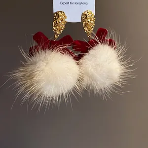 Detailed close-up of festive red velvet bow earrings with soft white fuzzy faux fur pom-poms