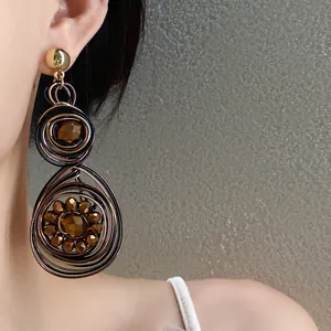 Detalle de pendientes vintage tejidos con cuentas de vidrio marrón facetadas de lujo
