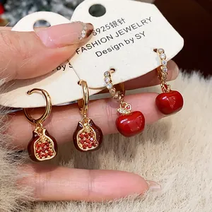Detailed macro view of gold plated pomegranate and apple earrings with zircon stones