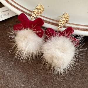 Close-up of red velvet bow earrings with fluffy white fur pom poms