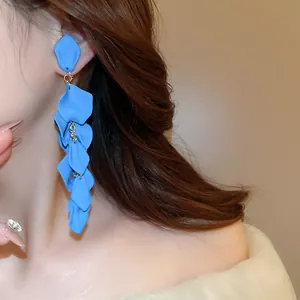 Detailed view of long blue matte flower petal tassel earrings worn on a female model's ear