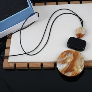 Macro view of geometric resin necklace with amber marble patterns and black cord