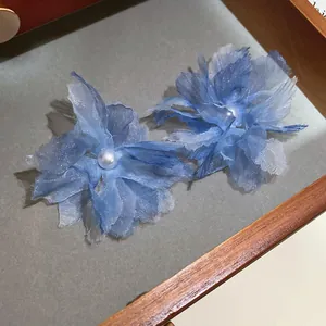 Primo piano di orecchini a fiore in rete blu con dettagli in perla per una vista dettagliata
