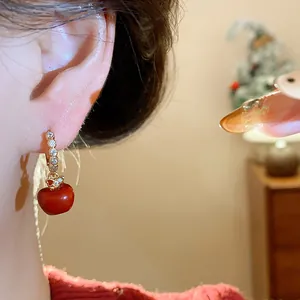 Close-up detail of a red apple pendant earring with a sparkling zircon gold hoop