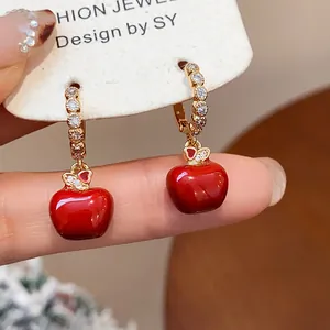 Close-up of red apple earrings with gold plating and sparkling zircon stones