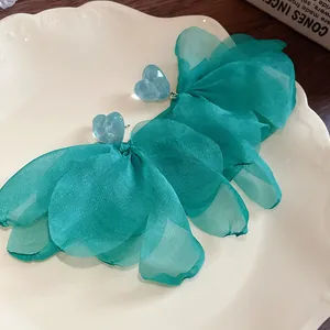 Dettaglio di orecchini a fiore in maglia d'organza verde acqua con cuori blu