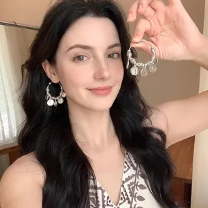 Fashionable exaggerated seaside vacation silver hoop earrings with coin charms on a model