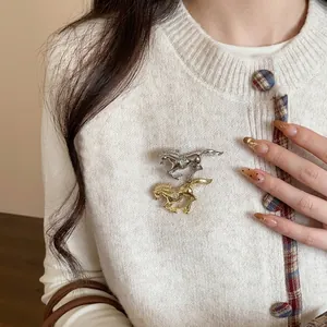 Elegant running horse brooches with diamonds in gold and silver on a white sweater
