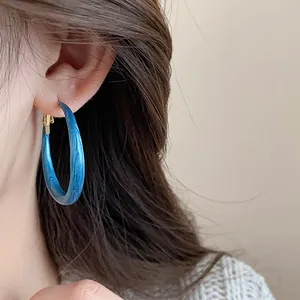 Close-up detail of a blue marbled texture hoop earring stylishly worn on a model's ear
