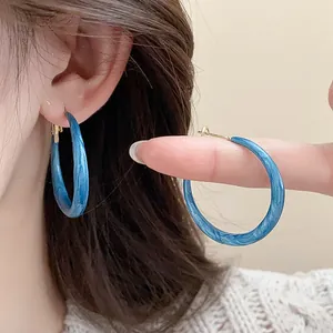 Detailed view of blue marbled dripping oil hoop earrings with silver needles