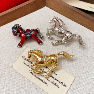 Close-up detail of three elegant horse brooches in red enamel, gold, and silver finishes