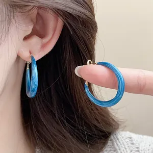 Detailed view of fashionable blue marbled oil-drop hoop earrings with silver needle posts