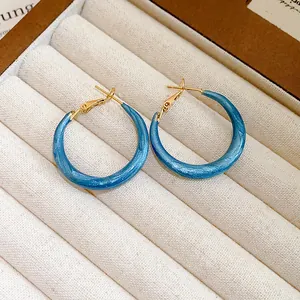 Detail view of blue marbled hoop earrings with gold-toned silver needle in tray