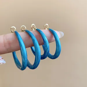 Close-up macro view of blue enameled hoop earrings with unique marble-like textures