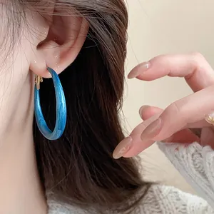Close-up of blue marbled enamel hoop earring with vintage retro charm.