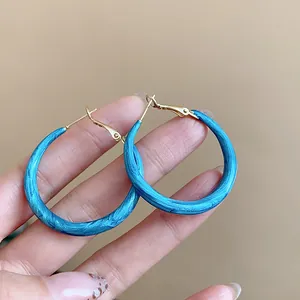 Close-up detail of blue marbled enamel hoop earrings featuring a polished gold finish