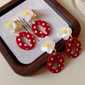 Detalle de pendientes de clip de flor de resina roja retro en bandeja