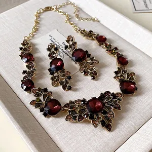 Détail de l'ensemble collier et boucles d'oreilles vintage avec feuilles et gemmes rouges
