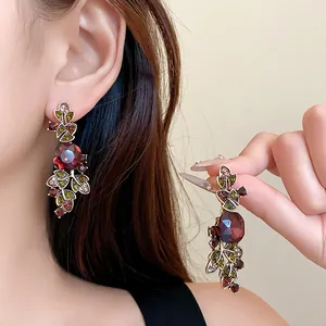 Gros plan de boucles d'oreilles vintage en forme de feuille avec strass rouges et verts.