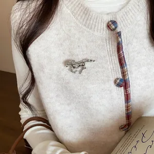 Elegant close-up of a silver rhinestone-encrusted horse brooch on a white knit cardigan