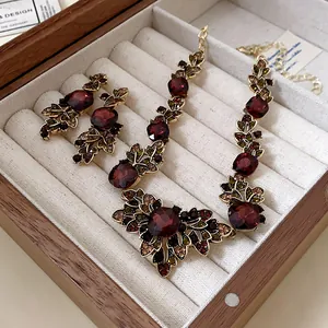 Détail d'un ensemble collier et boucles d'oreilles vintage en pierres bordeaux