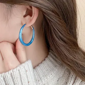 Close-up of blue marbled enamel hoop earring on model, elegant retro style jewelry