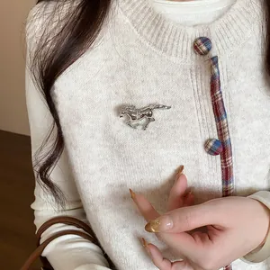 Detailed view of silver horse brooch with rhinestone inlay on a beige sweater.