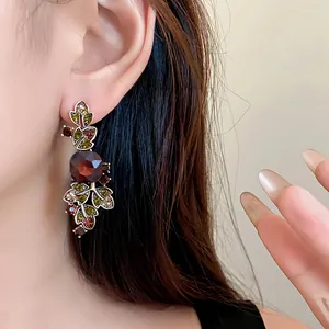 Gros plan d'une boucle d'oreille vintage en forme de feuille avec cristaux rouges.
