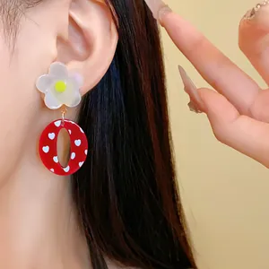 Detalle de pendientes vintage de resina roja con corazones blancos y flor arriba