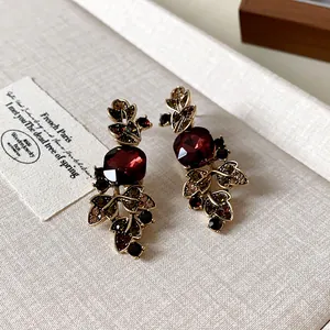Gros plan sur des boucles d'oreilles vintage avec pierres rouges et feuilles.