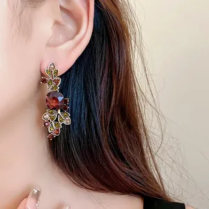 Détail en gros plan montrant des boucles d'oreilles feuilles vintage avec une pierre rouge.