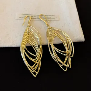 Macro view of elegant gold-toned tiered oval hollow earrings with pleated texture